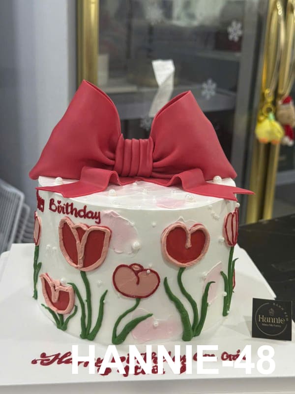 Bánh kem bơ Hannie nơ đỏ hoa tulip vẽ kem tinh xảo, sang trọng.